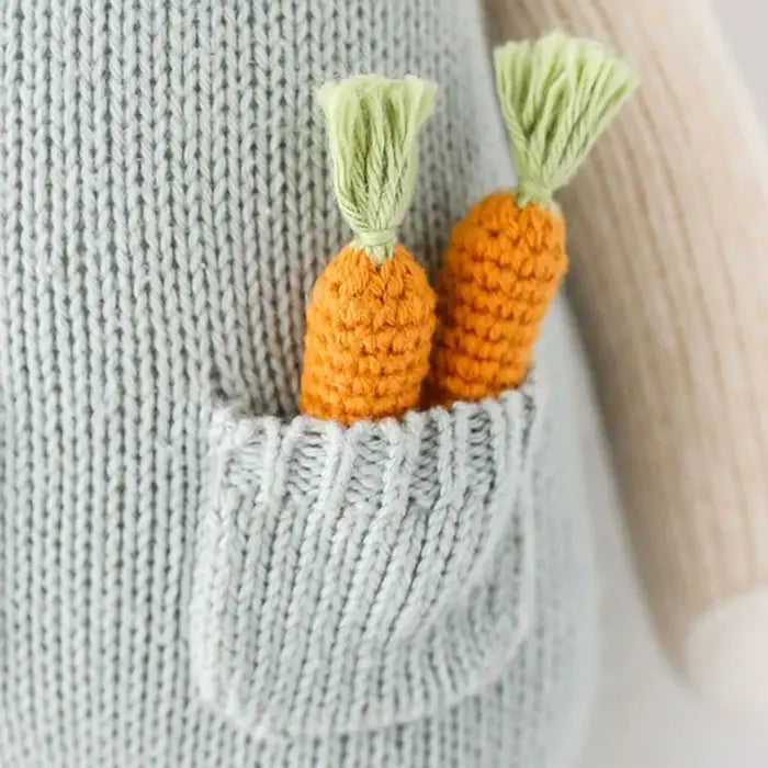 Two crochet carrots with green tops on a textured fabric background