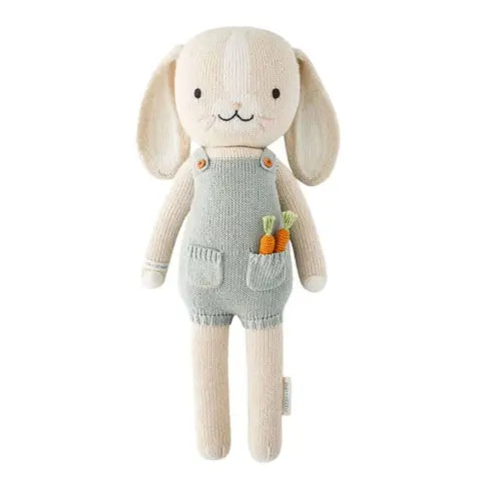 Stuffed toy rabbit in a green outfit with carrot decorations on a white background