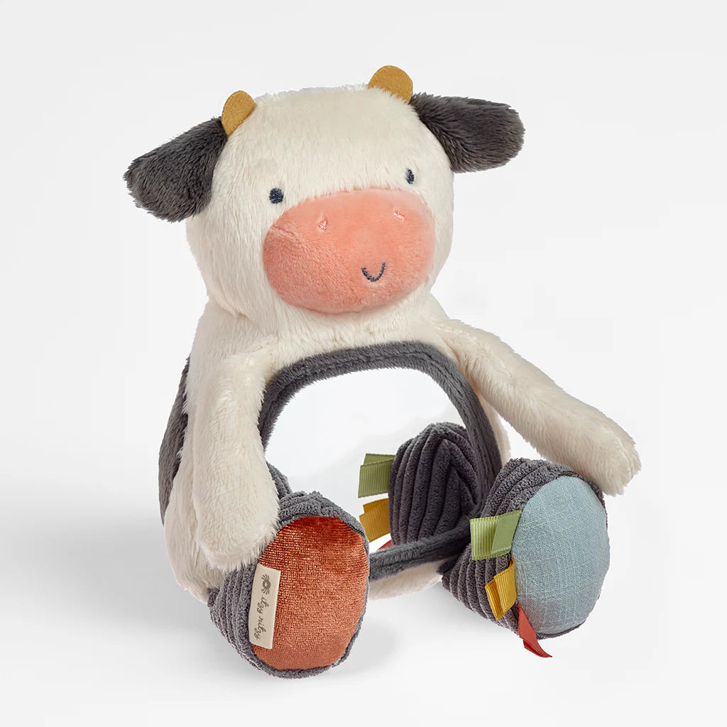 Plush cow toy with a textured leg on a white background