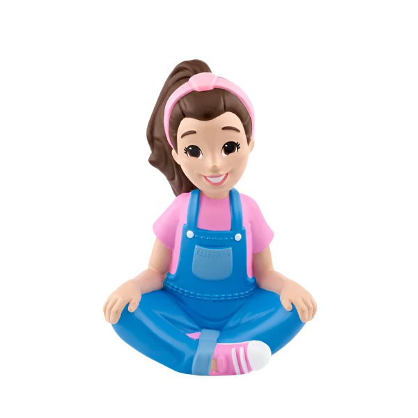 Toy figure of a girl wearing a pink shirt, blue overalls, and a pink headband on a light gray background